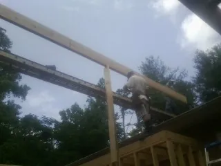 Carpenter setting a ridge beam over a new addition frame — Ice Dam Removal by Roofing Brothers in Colgate