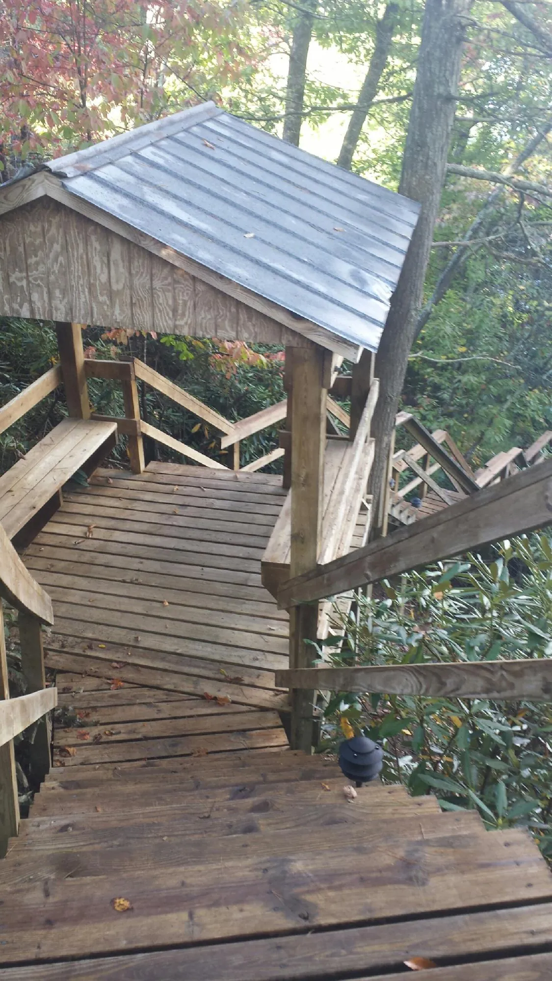 Metal roofed shelter over wooden steps on a wooded walkway — Skylight Repair & Installation work by our crew in Colgate