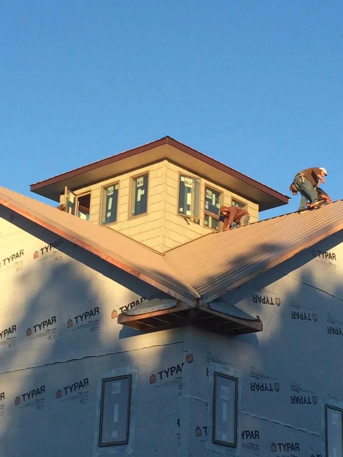 Roofers working around a rooftop cupola on a new metal roof at sunset — Roof Waterproofing in Colgate by Roofing Brothers